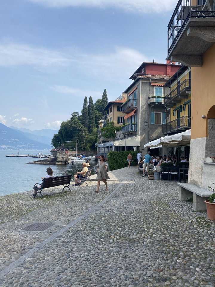 Un quai pavé au bord du lac de Côme, avec des maisons colorées et une terrasse de restaurant
